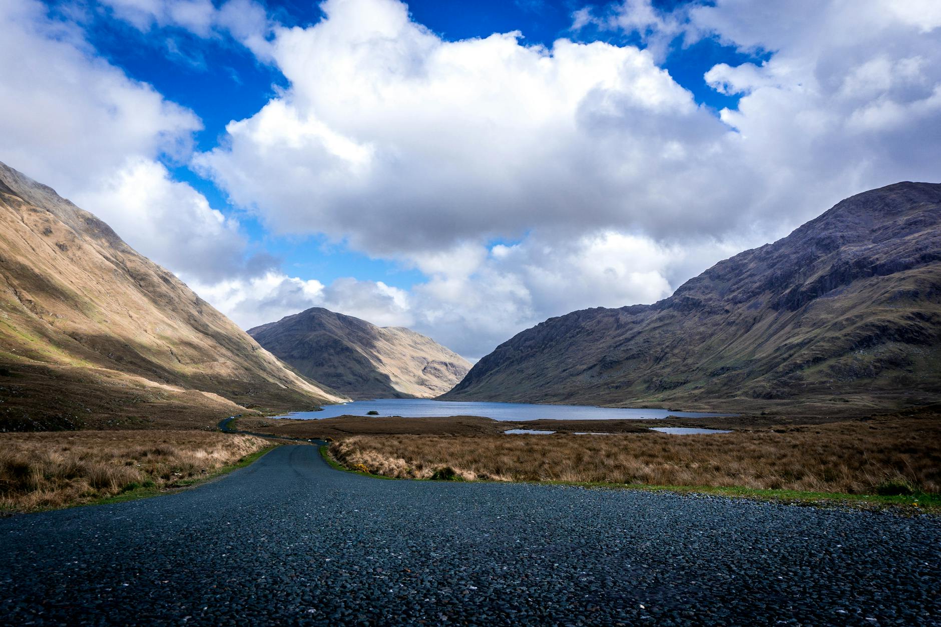 Objazdówka po Irlandii w 7 dni: gotowy plan podróży dla osób wynajmujących auto Górzysty krajobraz Irlandii z jeziorem pod błękitnym niebem