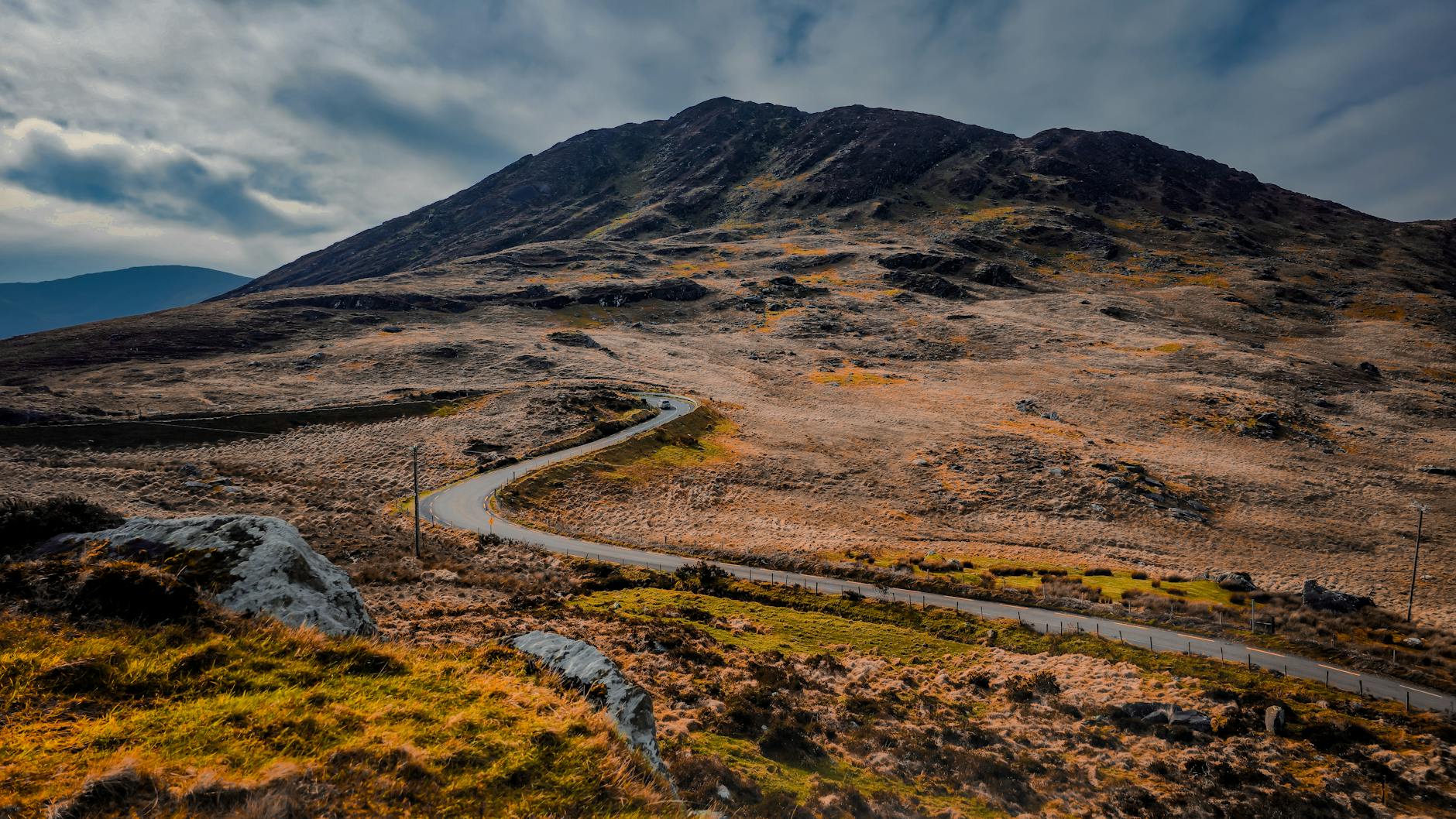 Kręta szosa wśród zielonych wzgórz i skał irlandzkiego krajobrazu