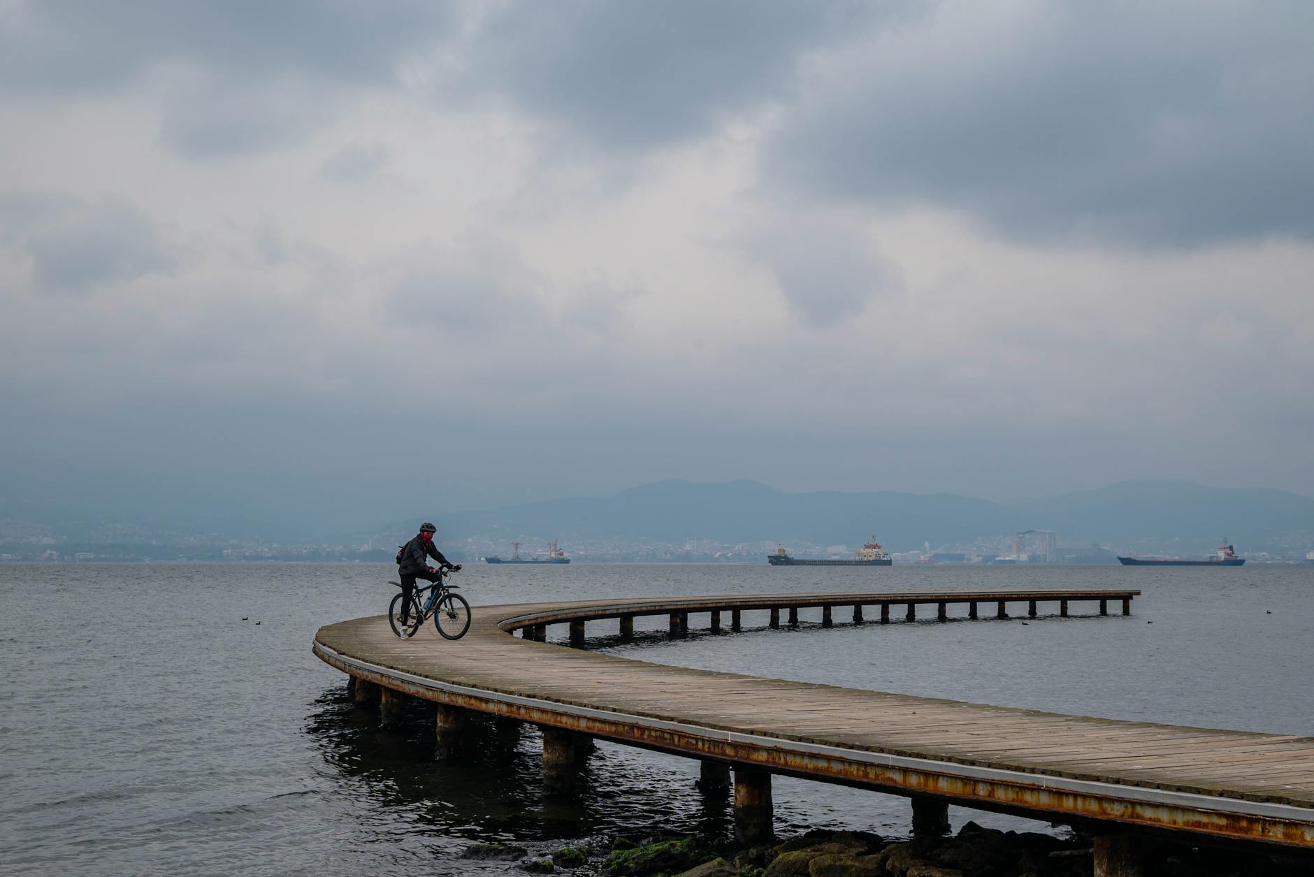 Samotny rowerzysta jedzie po krętym molo nad spokojnym Bałtykiem