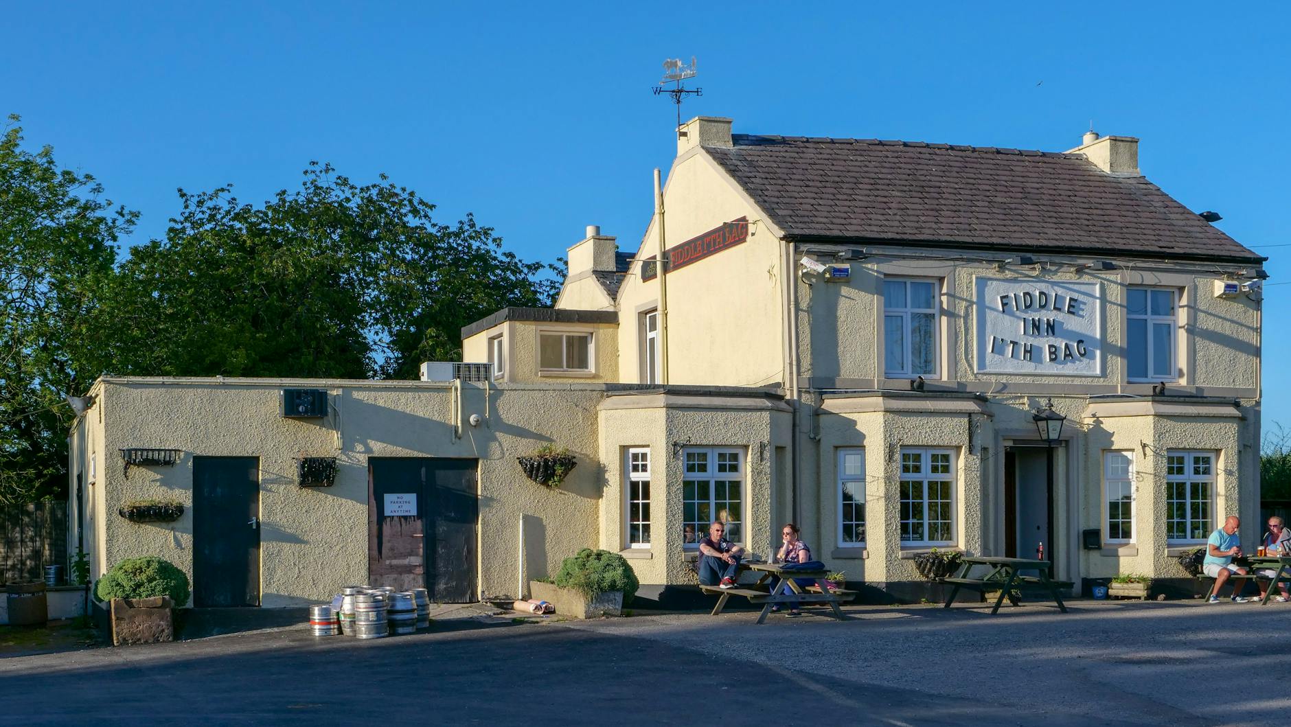 Letni ogródek tradycyjnego pubu w Burtonwood z mieszkańcami przy stolikach