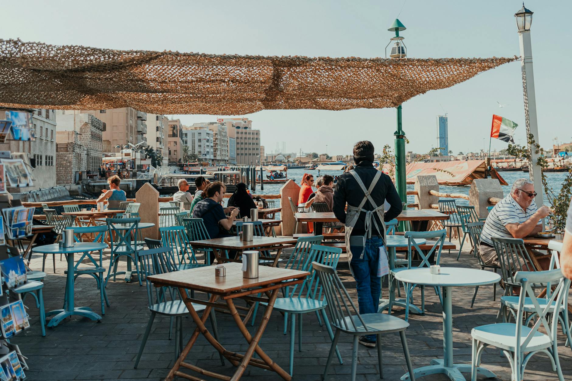 Ludzie w plenerowej kawiarni nad Dubai Creek w słoneczny dzień