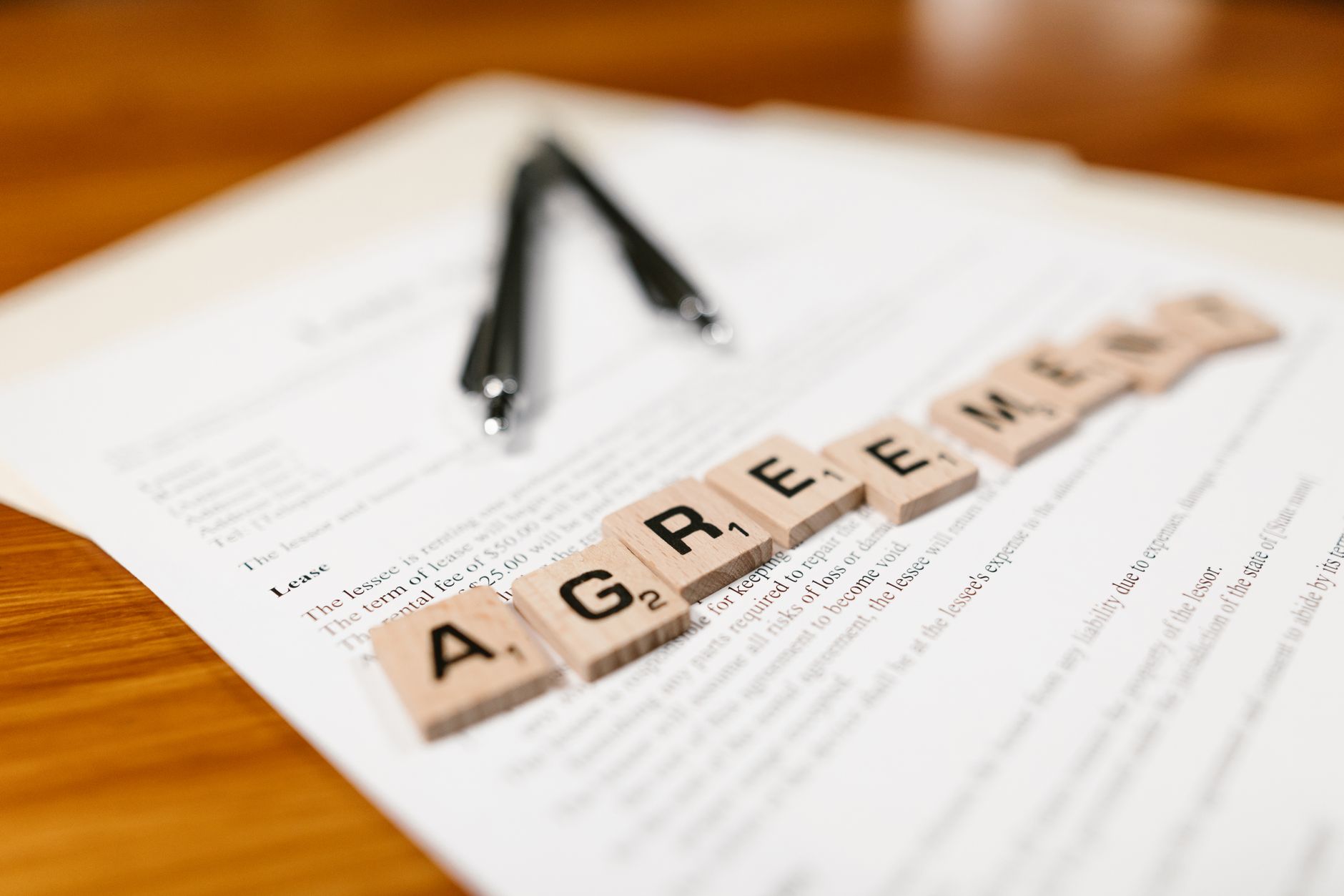Kafelki Scrabble z napisem AGREEMENT leżące na dokumencie leasingu