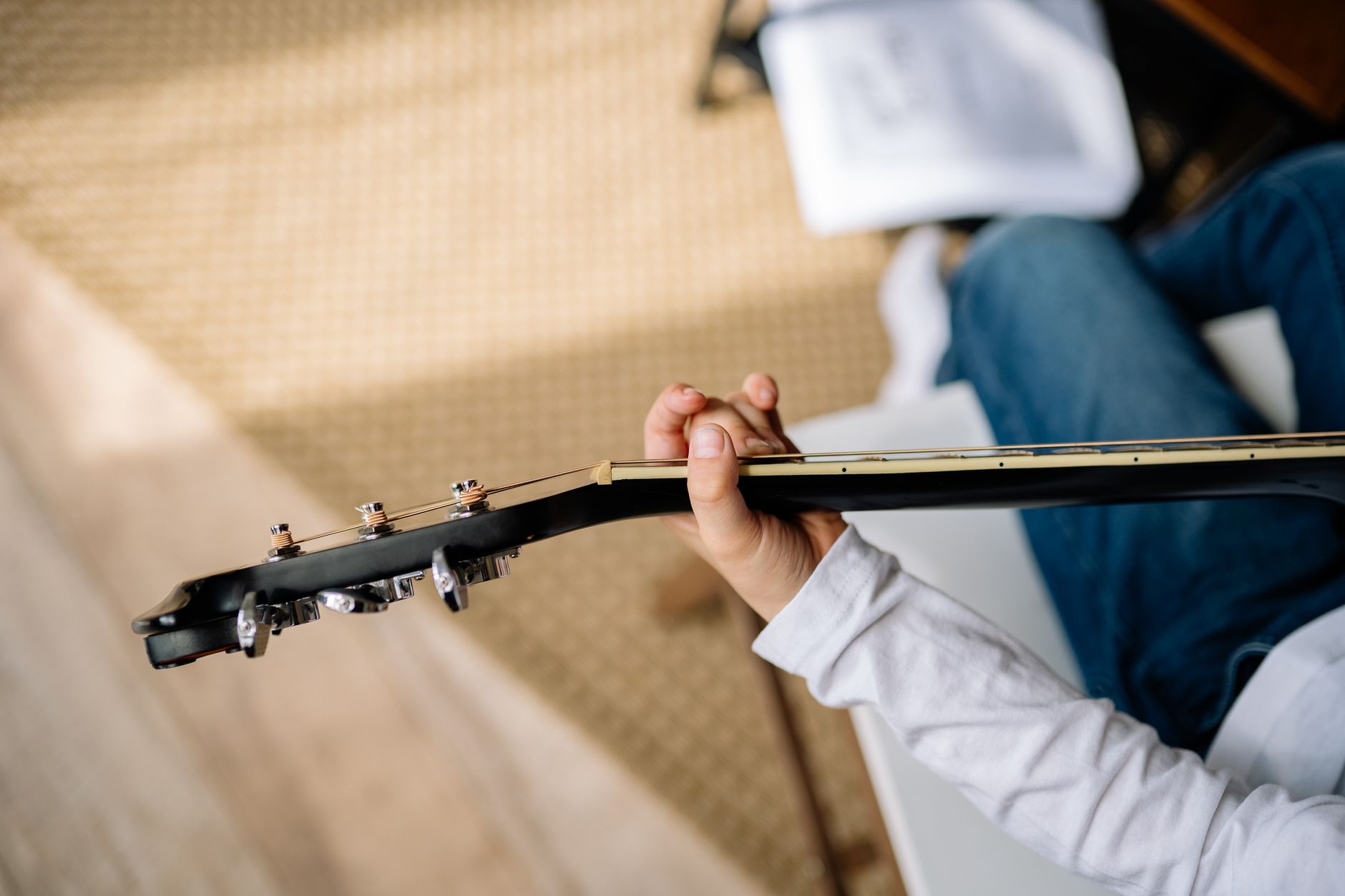 Osoba w białej koszuli ćwiczy technikę gry na gitarze akustycznej