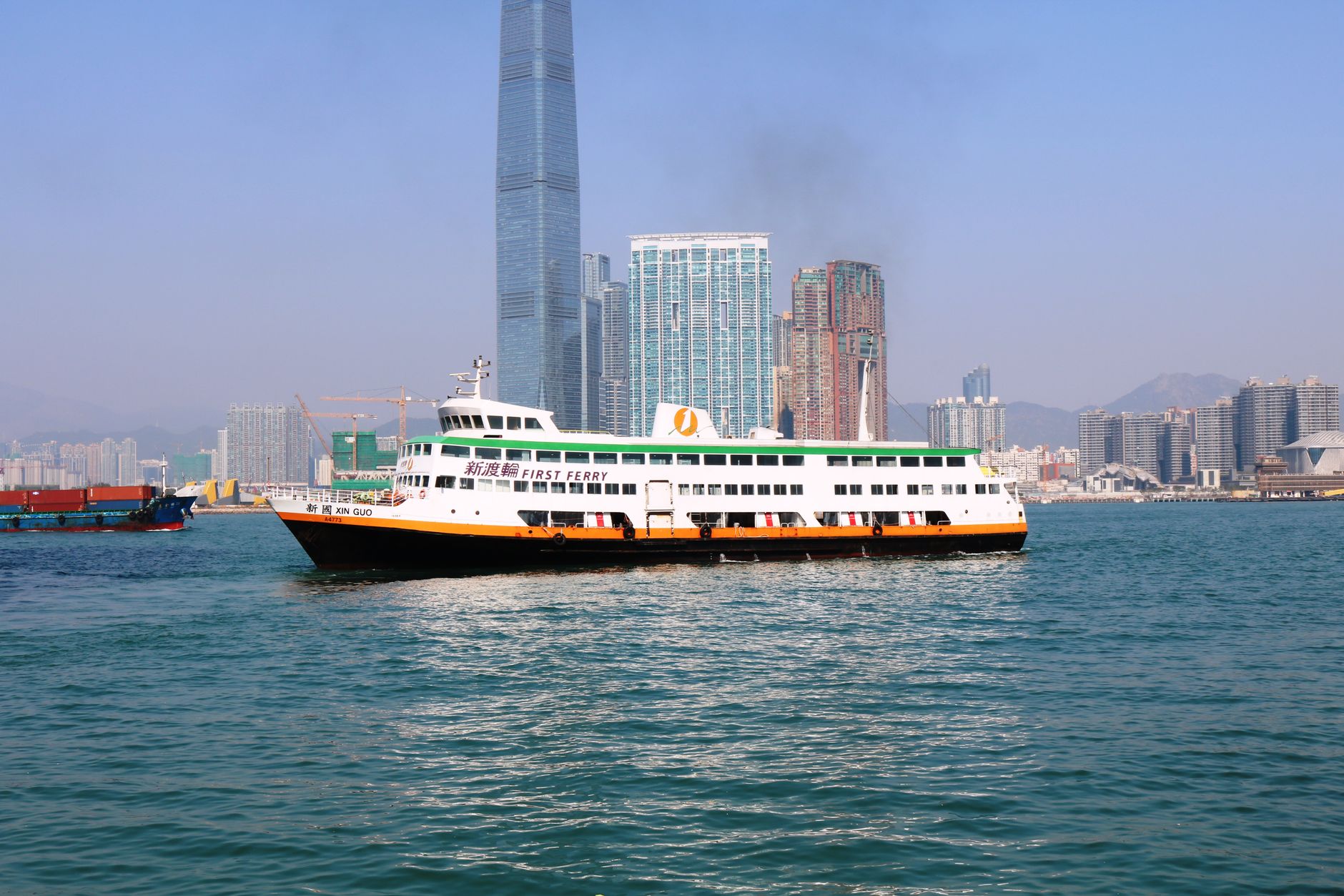 Prom pasażerski płynie przez Victoria Harbour na tle panoramy Hongkongu