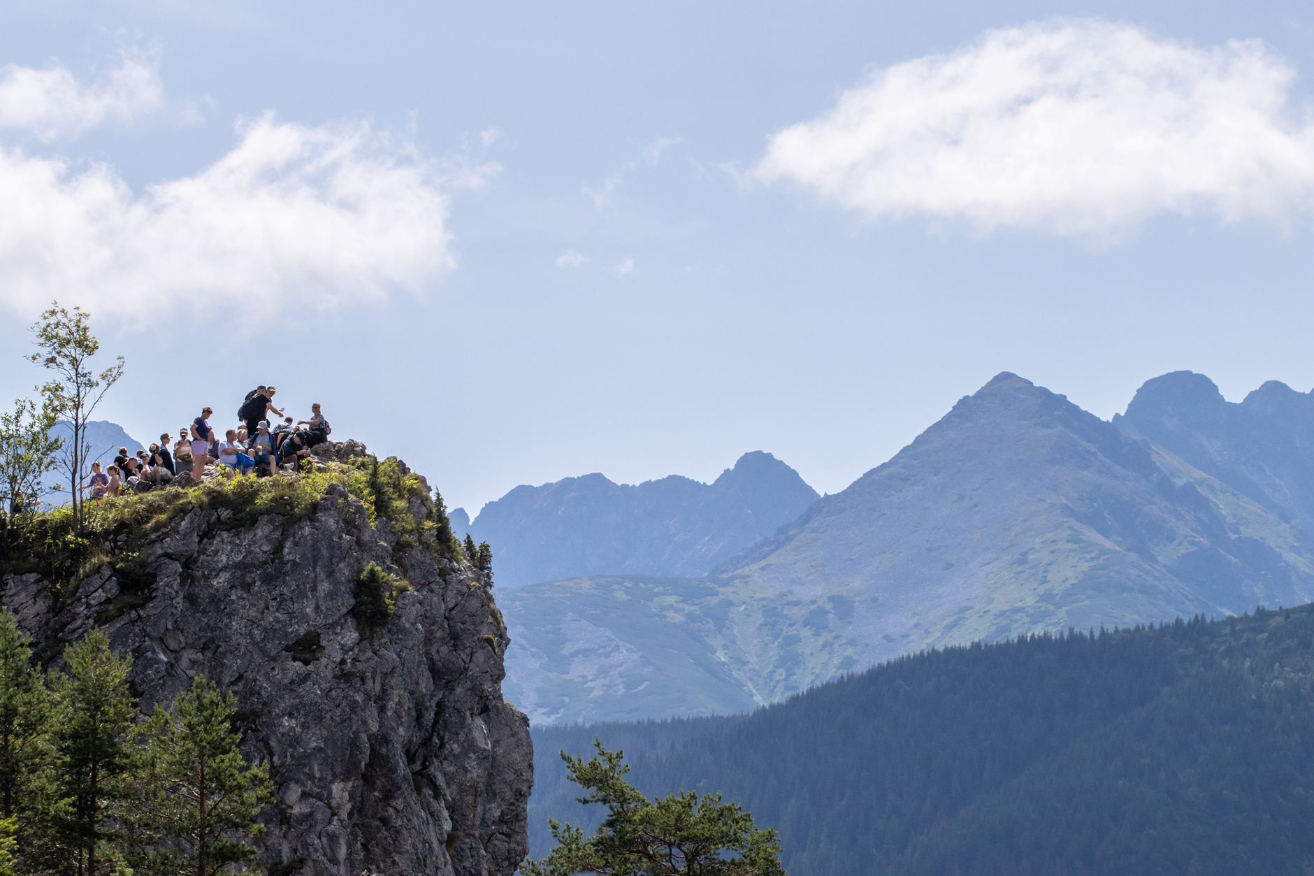 Turyści na skalnym klifie w Tatrach podziwiają panoramę gór