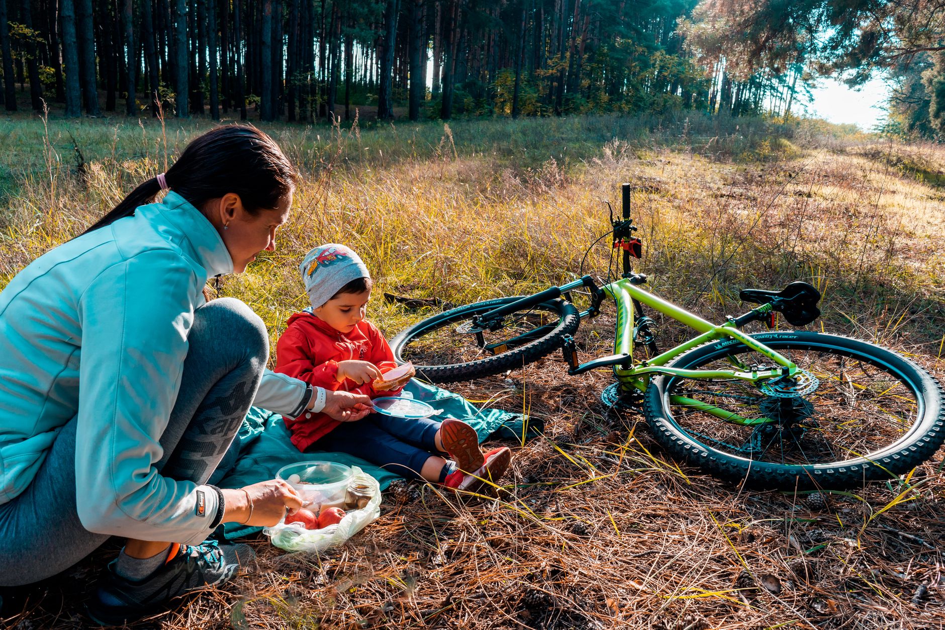 Mama z synem na pikniku w lesie, obok stoi rower trekkingowy