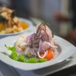 Kolorowe peruwiańskie ceviche na białym talerzu z dodatkami